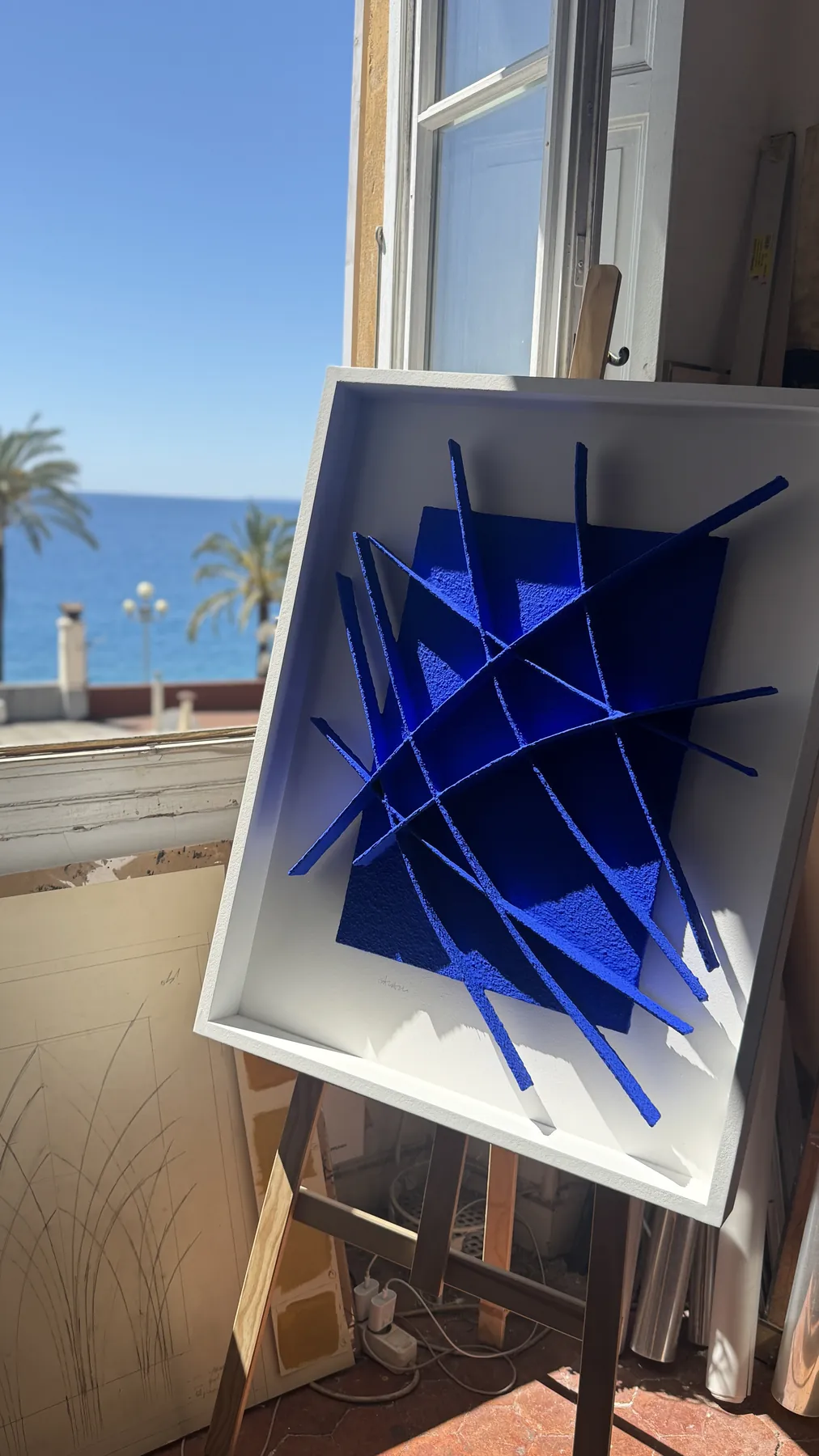 Œuvre bleue posée face à la fenêtre et à la mer